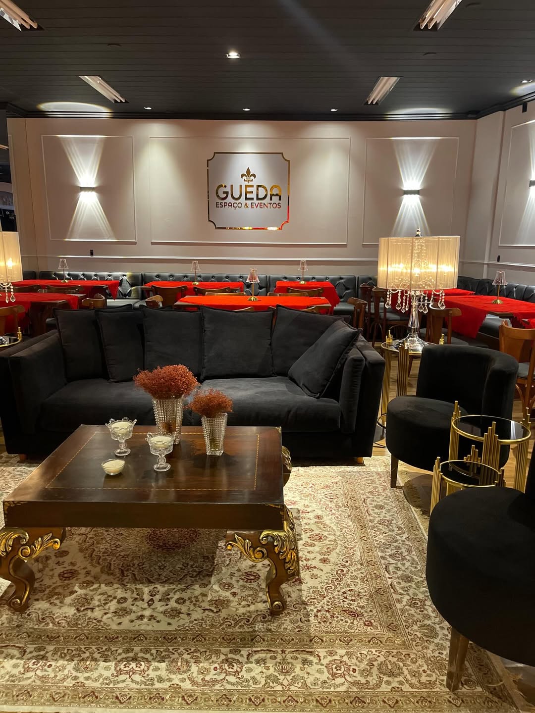 Lounge com sofá, logo Gueda e mesas em vermelho