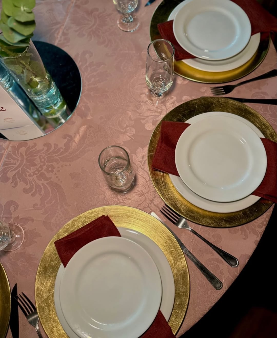 Mesa posta com sousplat dourado e guardanapo bordô